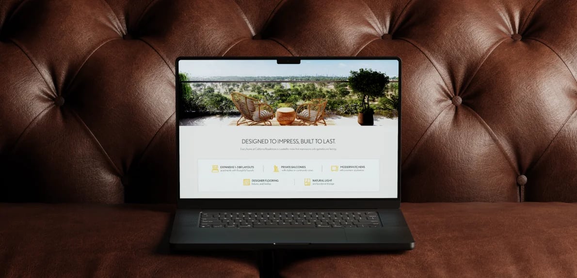 Laptop on a brown chesterfield showing a website: “DESIGNED TO IMPRESS, BUILT TO LAST”
