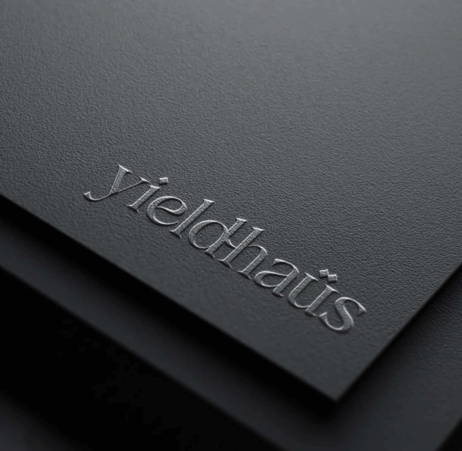 Embossed yieldhaüs wordmark on a black card