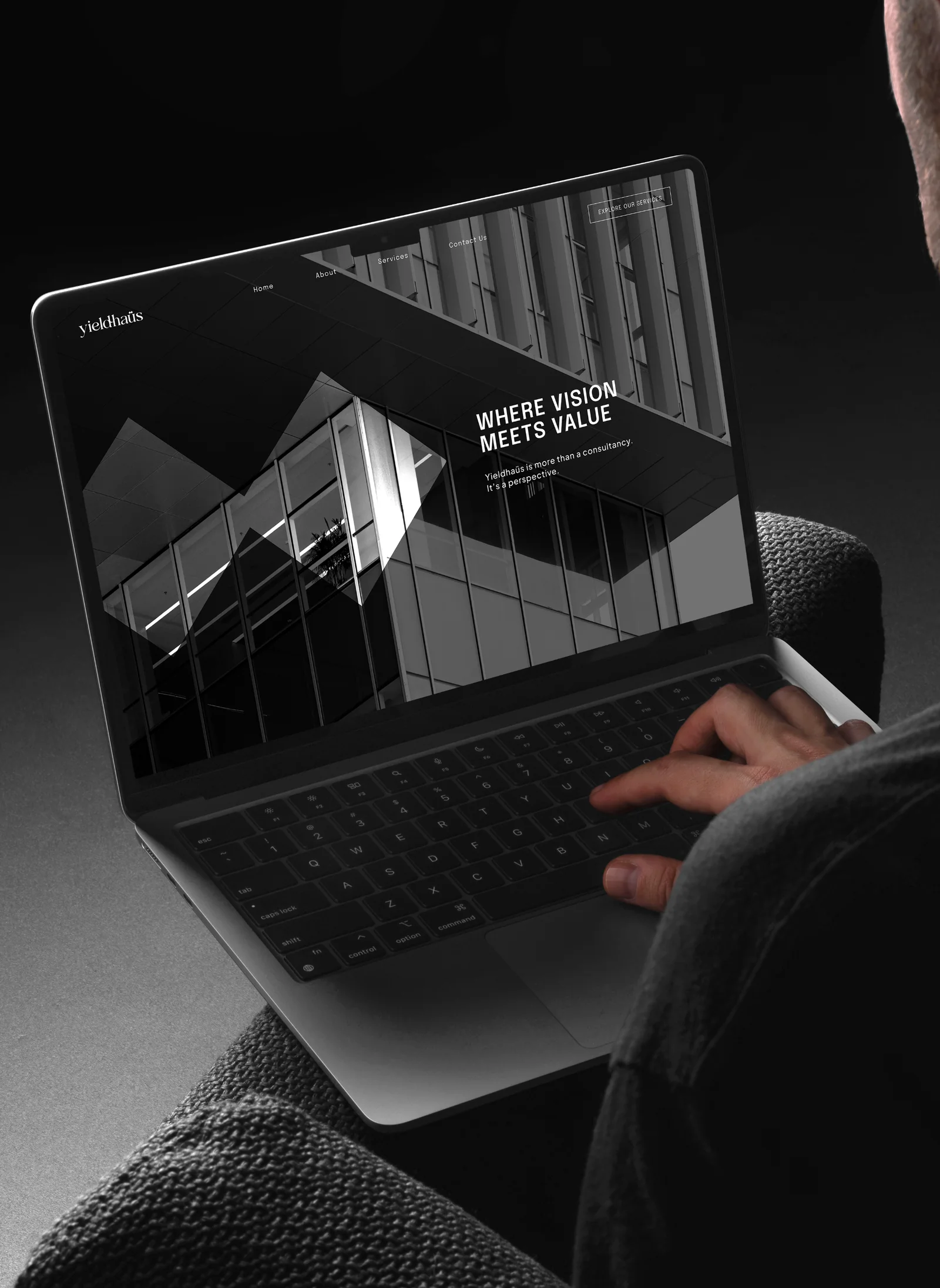 Man typing on a laptop showing the Yieldhaüs website: “WHERE VISION MEETS VALUE”
