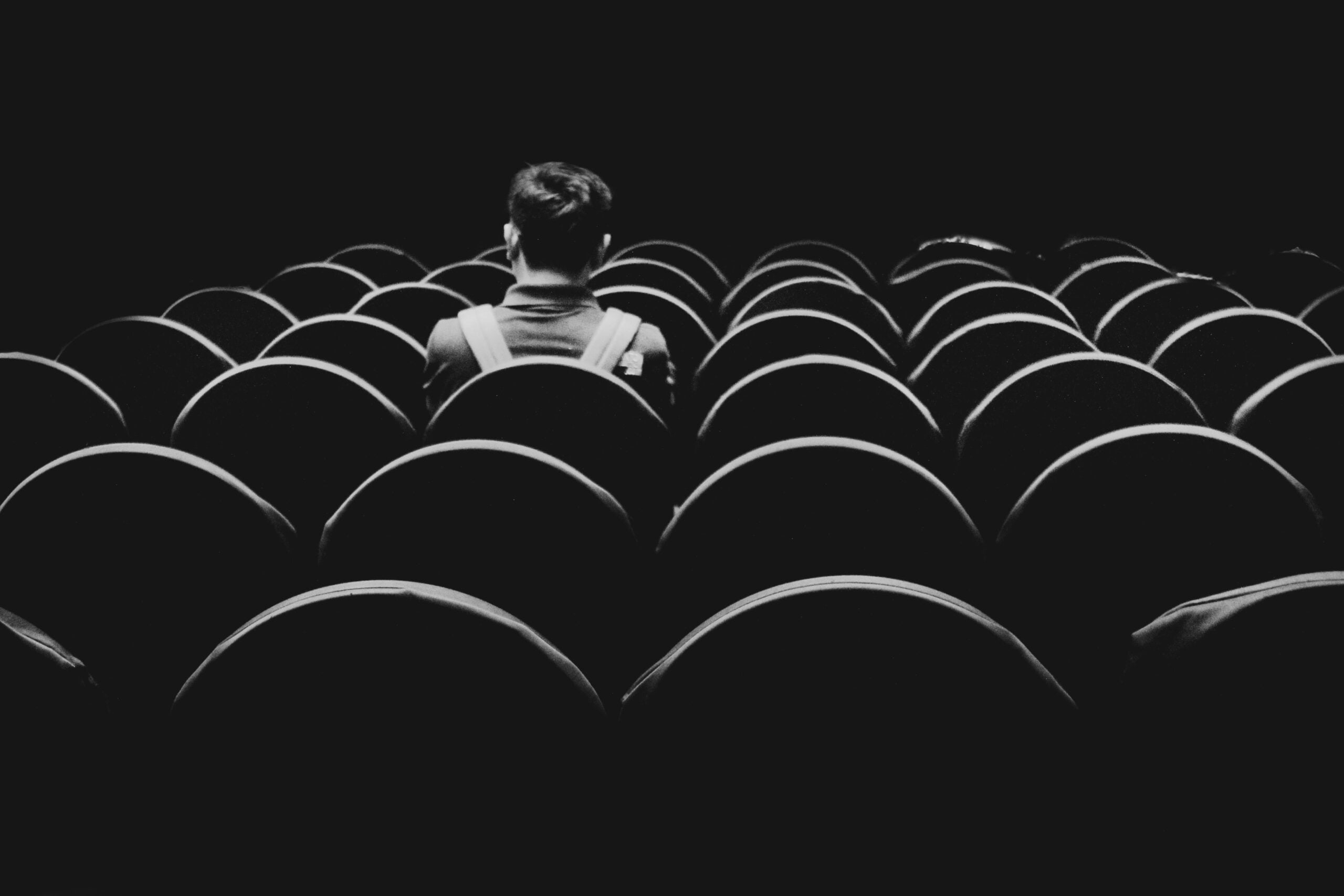 Person sitting alone inside an empty theatre