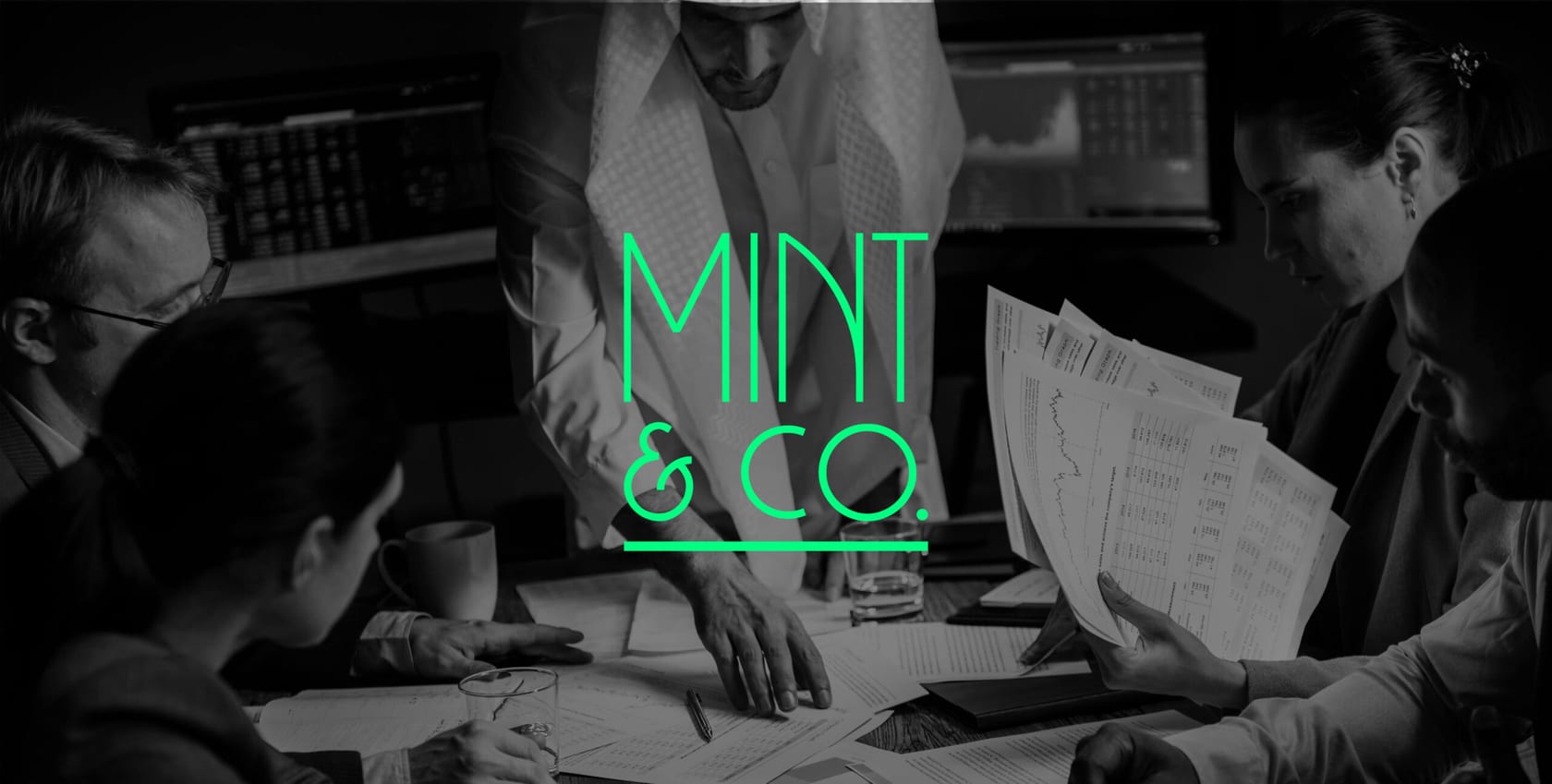Team reviewing financial charts with Mint & Co. logo overlaid