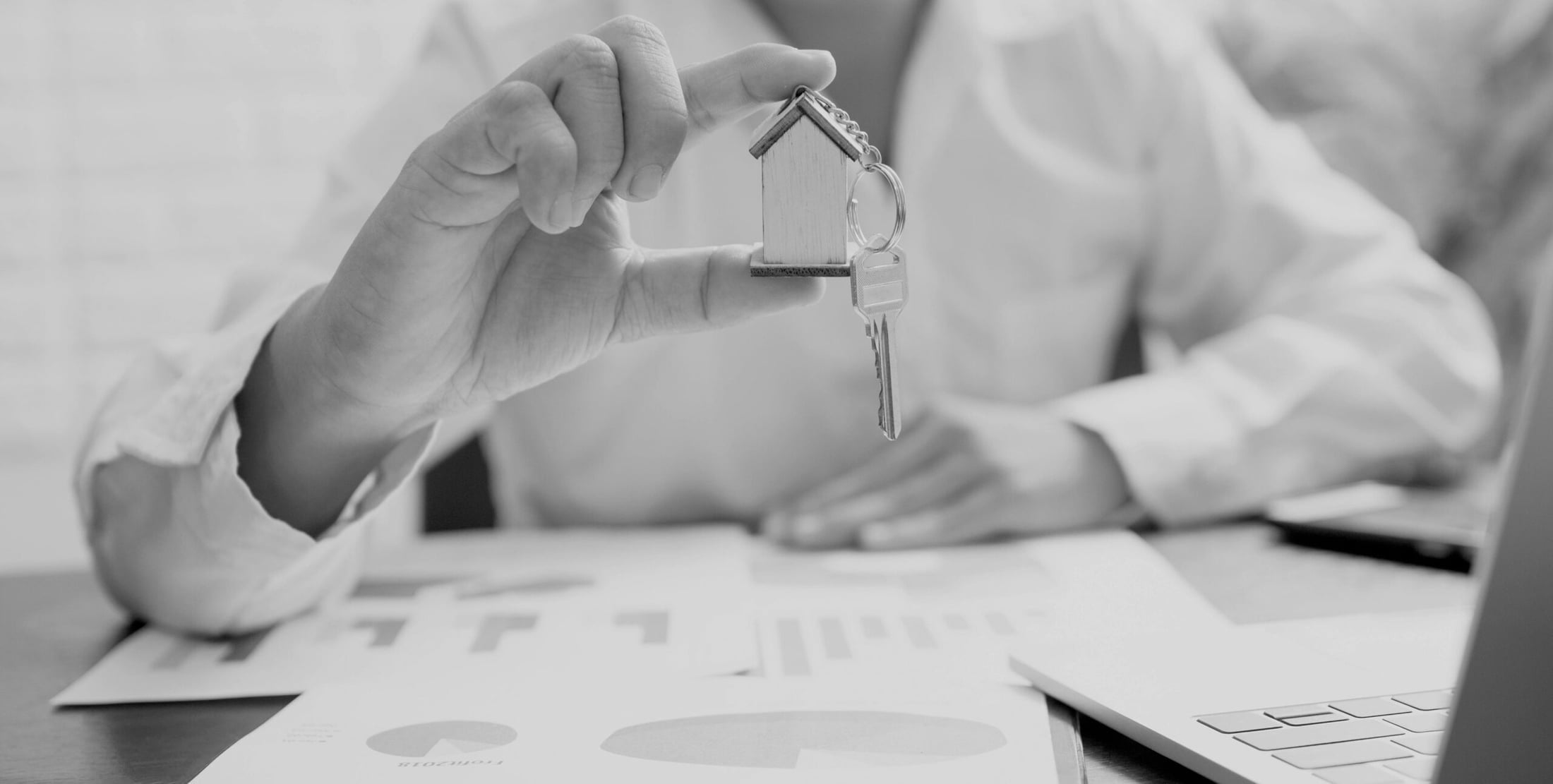 House-shaped keychain over property documents, real estate purchase handover