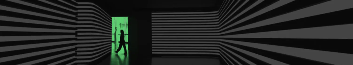 A figure walking through a lit doorway at the end of a striped corridor