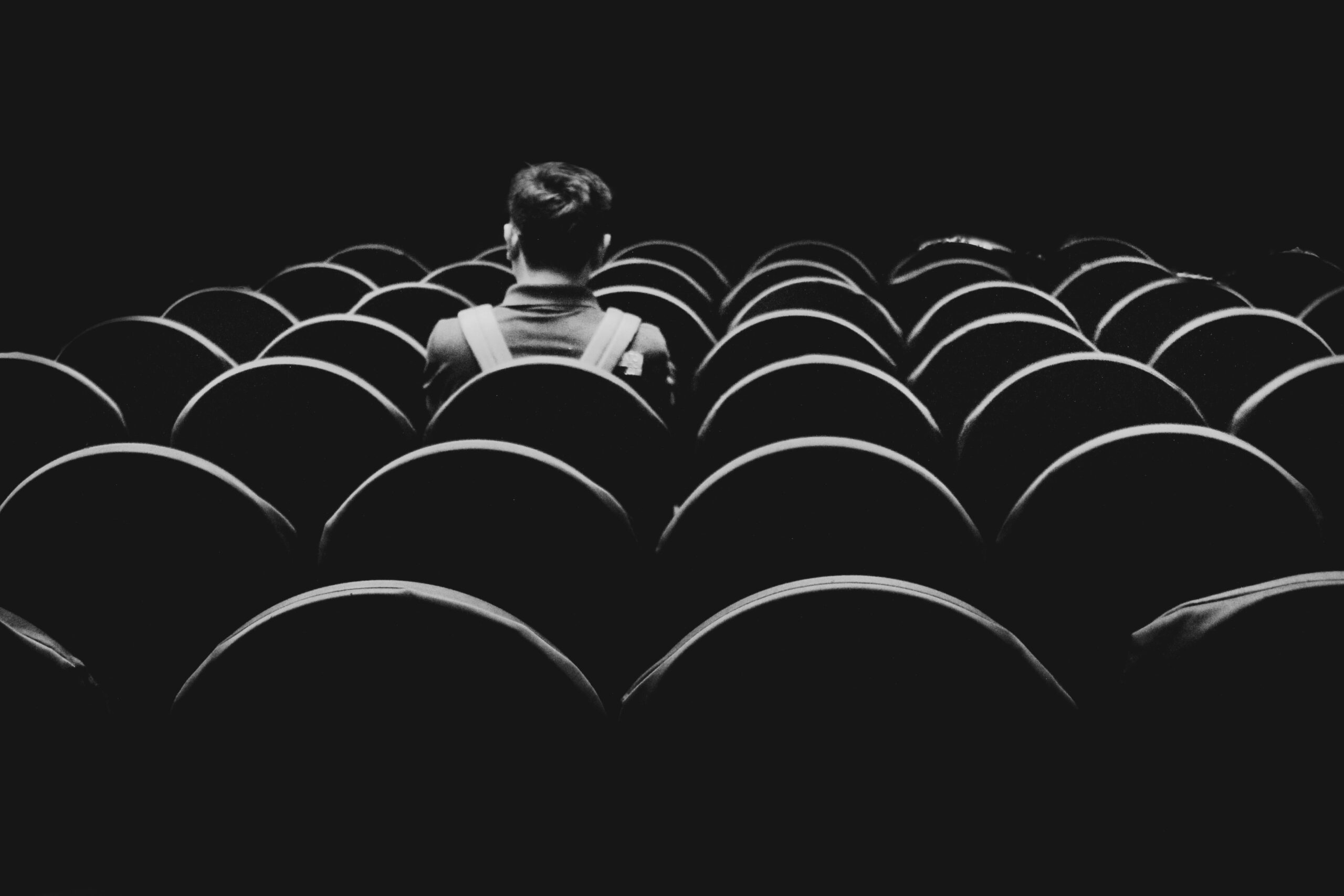 Person sitting alone inside an empty theatre